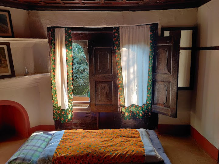 Bedroom window with traditional wooden shutters opening to a garden view