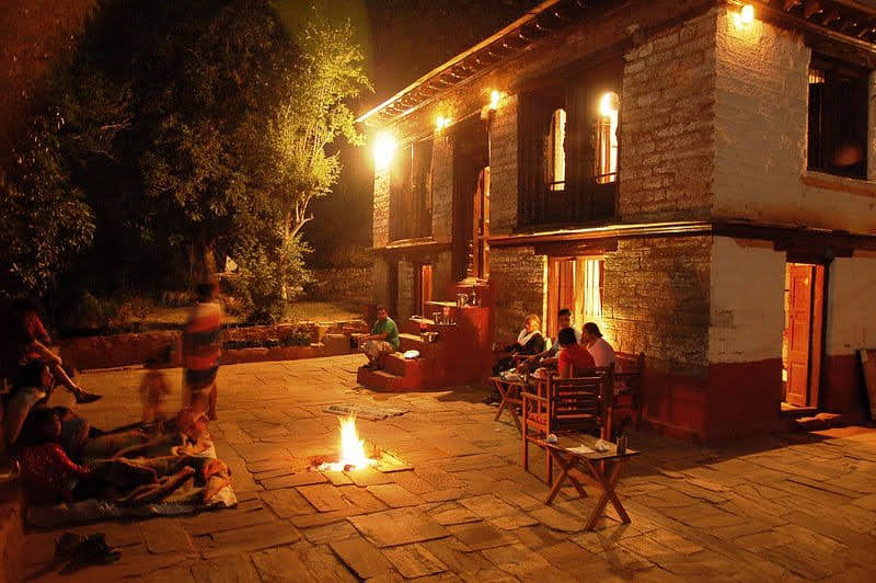 Guests sitting around a bonfire in the courtyard at night