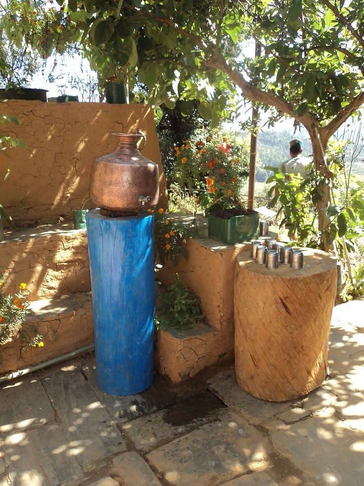 Traditional copper water pot (lota) displayed on a blue wooden pedestal