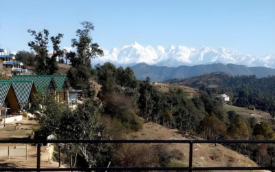 Row of modern A-frame cottages with private balconies facing snow-capped mountains.