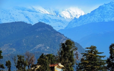 Close-up view of majestic snow-capped mountains over forested hills