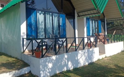 Two white cottages with green roofs and private patios with black railings.
