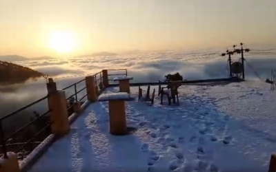 Snowy viewpoint deck with tables overlooking a sea of clouds