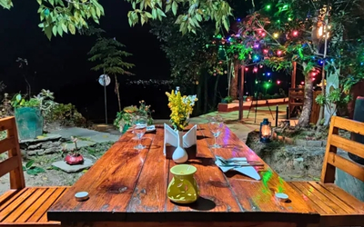 Outdoor wooden table set for dinner with string lights and candles at night