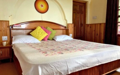 Cozy double bedroom with wooden paneling and colorful pillows