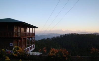 A wooden cottage balcony view of the Himalayan snow peaks at sunset